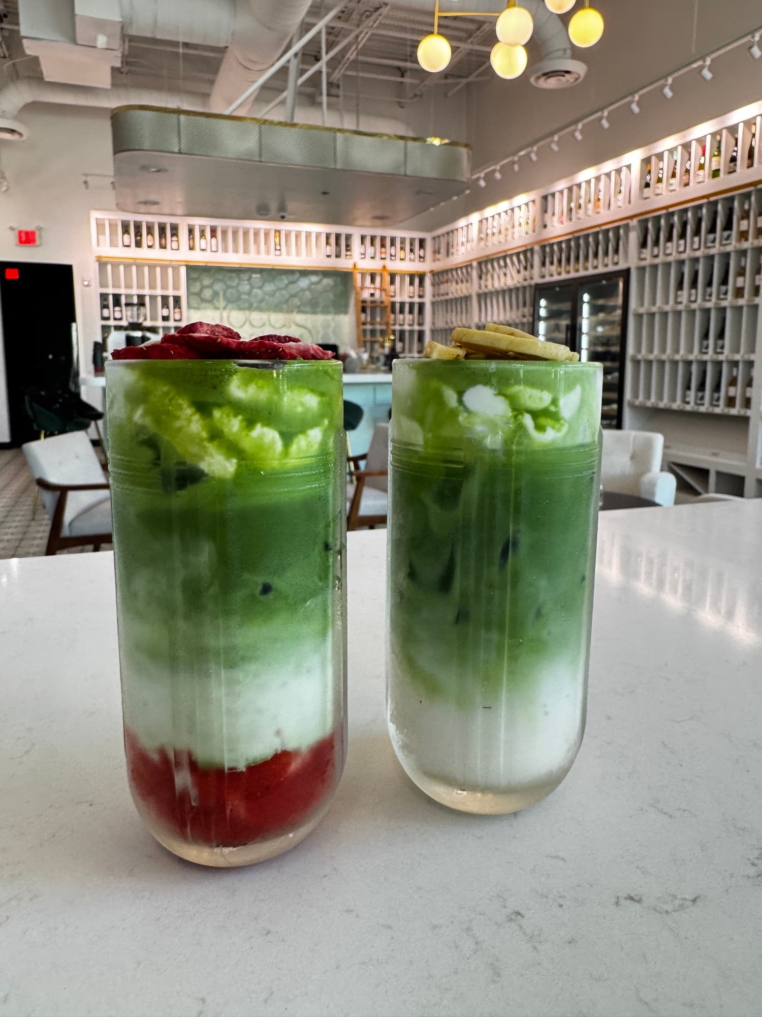 Layered matcha and strawberry drinks on the white bar at Locals